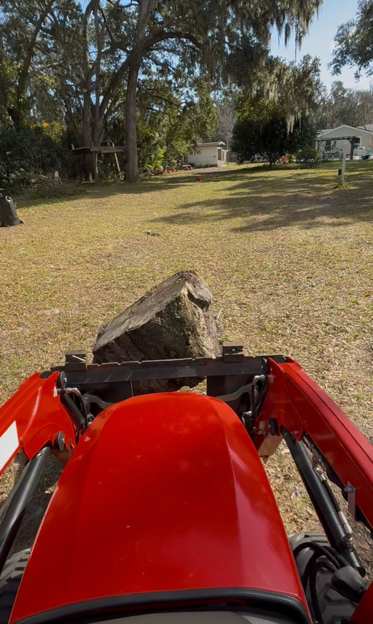 View from the Little Tractor Co compact tractor carrying a small stump during property cleanup
